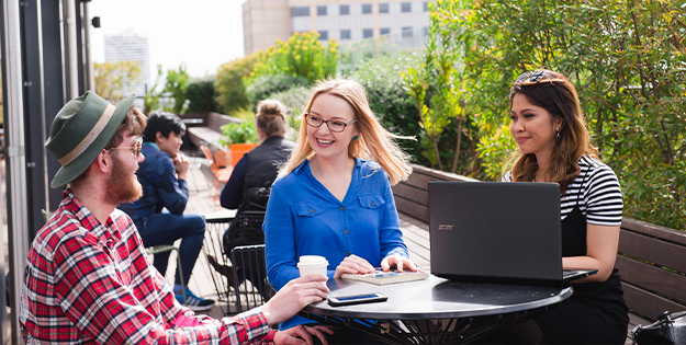 Three friends sitting at the rooftop cafe at ACU Melbourne.