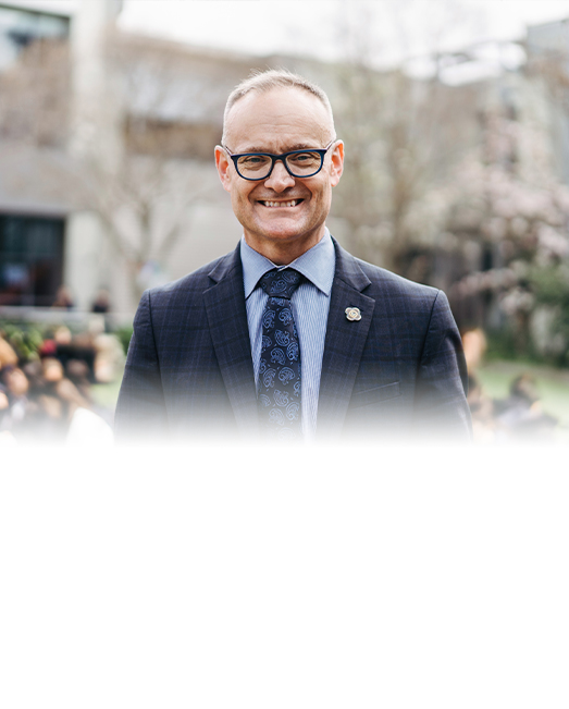 Brendan Watson smiling to camera with his school campus in the background