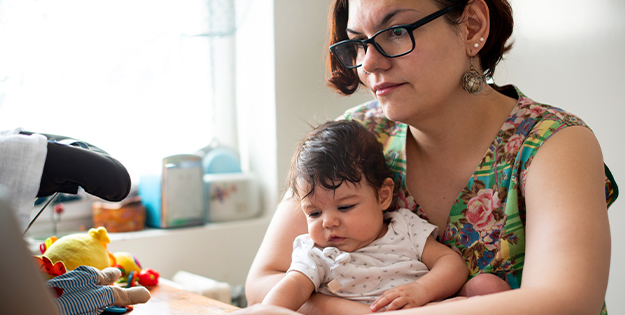 Mother working at laptop with baby in lap