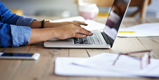 Hands typing on a laptop