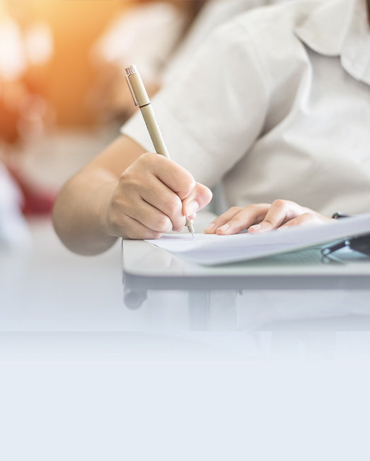 Student writing in an exam with a pen.