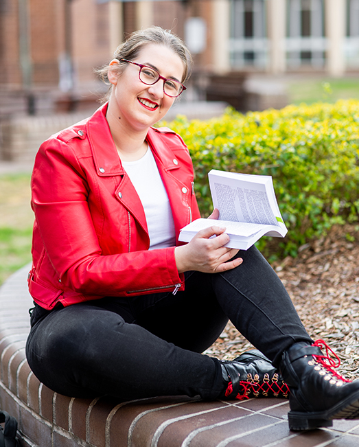 Helena Citroni sitting in the campus gardens reading.