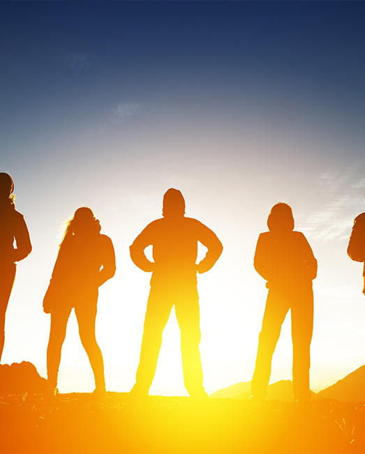 Five young people silhouetted against rising sun
