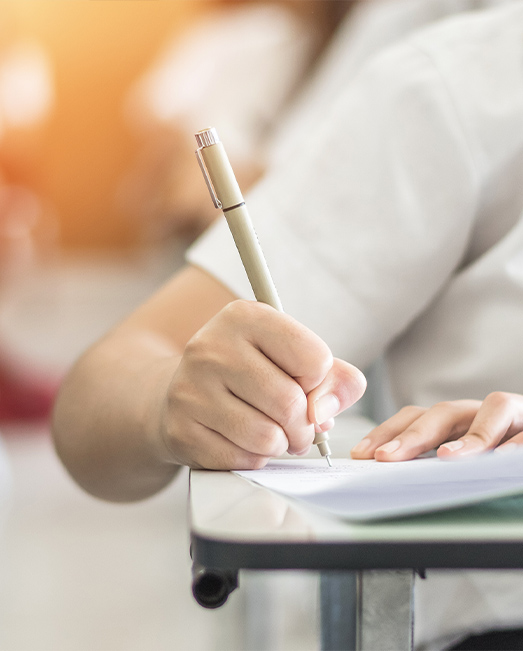 Student writing in an exam with a pen.