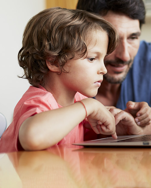 Toddler typing on computer with father