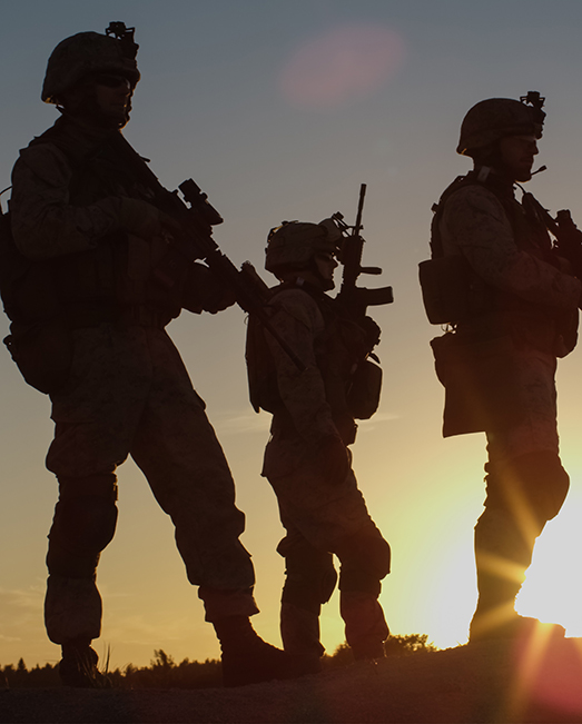 Three armed soldiers in silhouette again the sunset