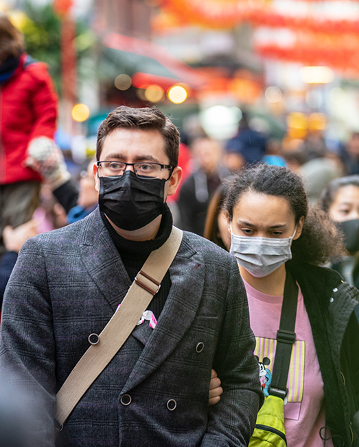 Man and woman walking down street wearing face mask