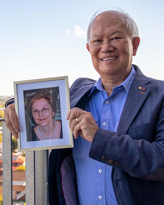 Emeritus Professor Darryl Low Choy holding framed image of wife Nancy