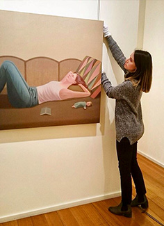 Jessica hanging a painting for an exhibition