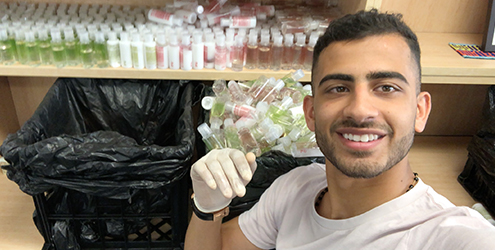 George smiling at camera while packing shampoo donations for the homeless