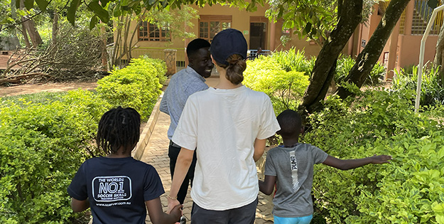 Kristen holding hands with children in Uganda.